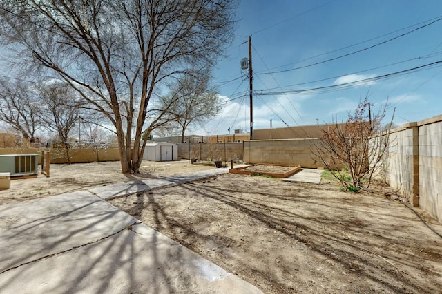 view of yard with an outdoor structure, a fenced backyard, a storage shed, and a patio area