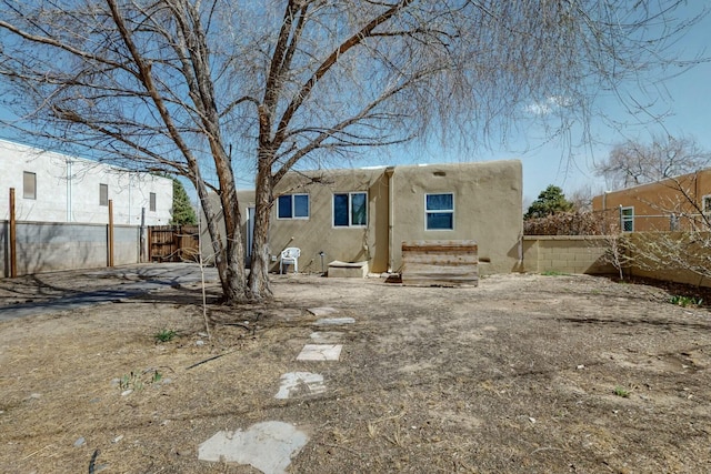 rear view of property with stucco siding and fence