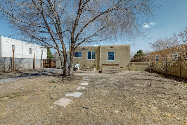 back of house featuring stucco siding and fence