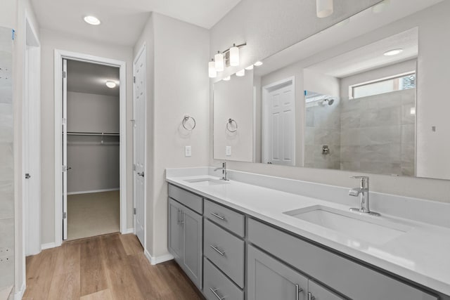 8401 Twain Way NW, Albuquerque, NM 87114 - full bathroom with wood finished floors, a tile shower, double vanity, a walk in closet, and recessed lighting
