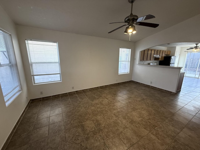 unfurnished living room with lofted ceiling, a ceiling fan, and baseboards