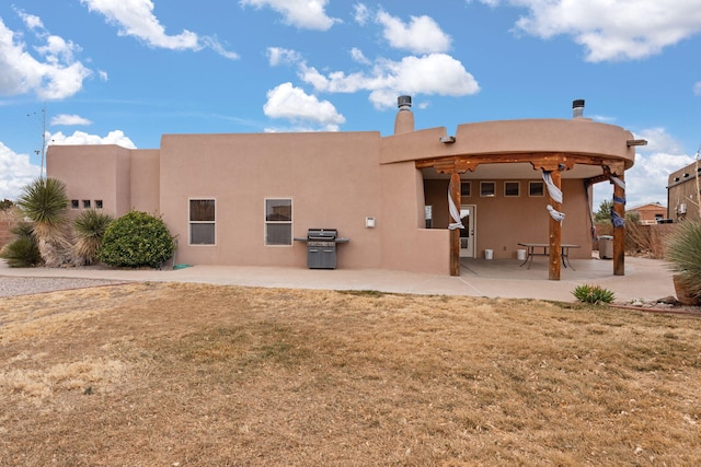 back of property featuring a patio, a lawn, and stucco siding