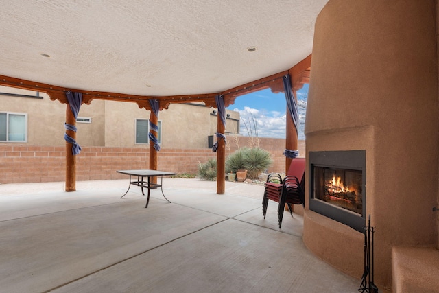 view of patio / terrace with a lit fireplace and a fenced backyard