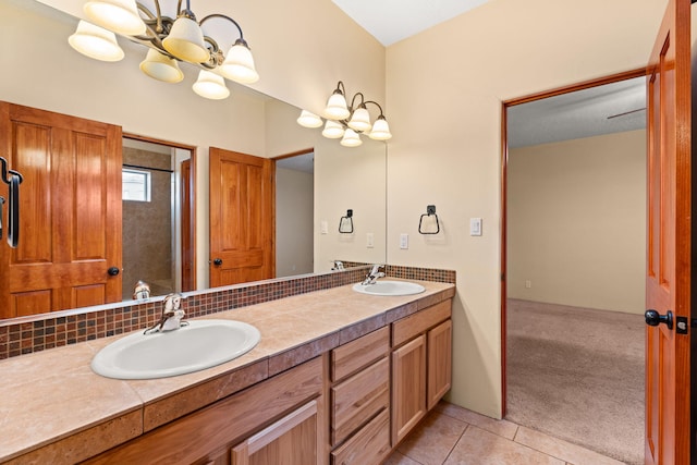 bathroom with tile patterned floors, a notable chandelier, double vanity, and a sink