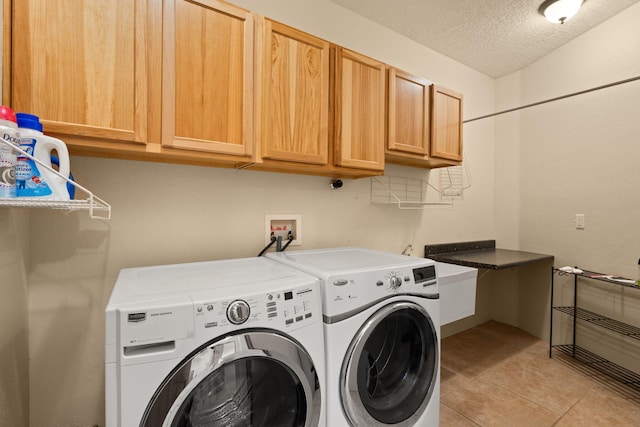 washroom with light tile patterned floors, cabinet space, independent washer and dryer, and a textured ceiling