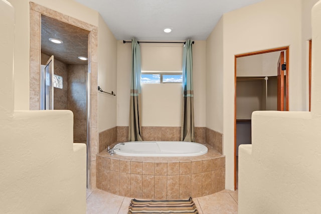 full bathroom featuring a bath, a shower stall, and tile patterned flooring