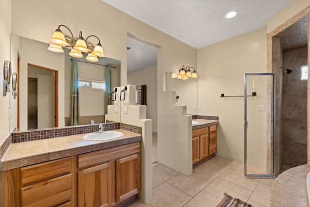 bathroom with two vanities, a sink, a textured ceiling, tile patterned flooring, and tiled shower