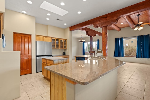 kitchen with beam ceiling, a sink, a spacious island, appliances with stainless steel finishes, and glass insert cabinets