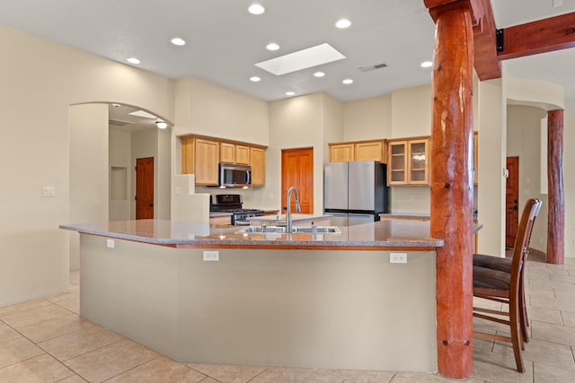 kitchen featuring visible vents, a sink, stainless steel appliances, light tile patterned floors, and a large island with sink