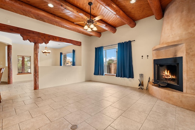 unfurnished living room with beamed ceiling, ceiling fan with notable chandelier, wooden ceiling, a fireplace, and light tile patterned flooring