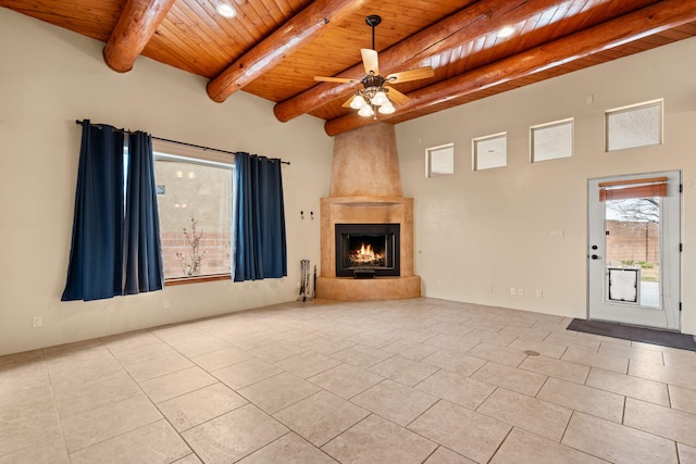 unfurnished living room with beamed ceiling, wooden ceiling, a large fireplace, and ceiling fan