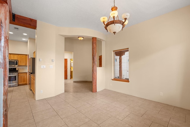 empty room with light tile patterned floors, visible vents, arched walkways, and a chandelier