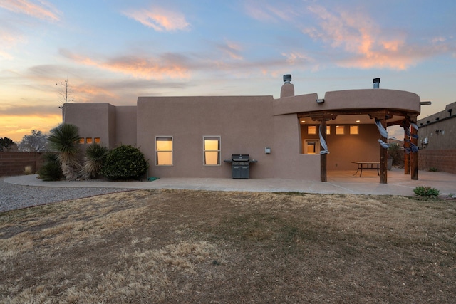 rear view of property with a patio, a lawn, a chimney, and stucco siding