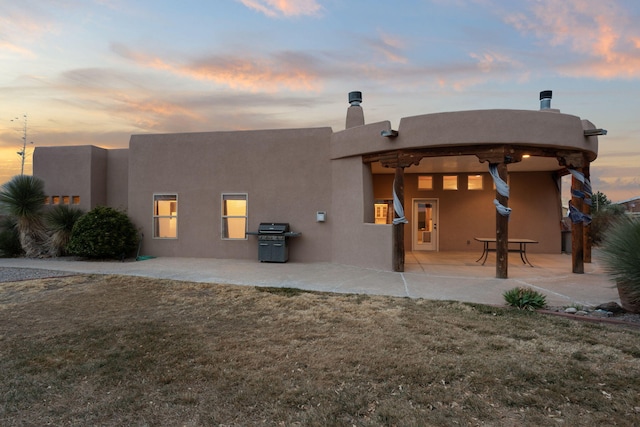 back of house featuring stucco siding, a yard, and a patio area