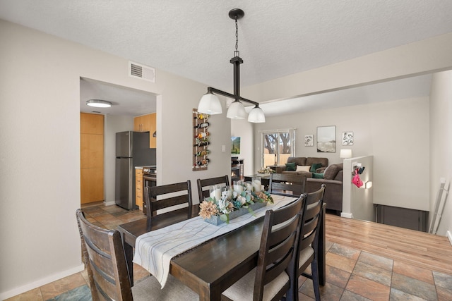 dining area featuring visible vents, a textured ceiling, and stone tile flooring