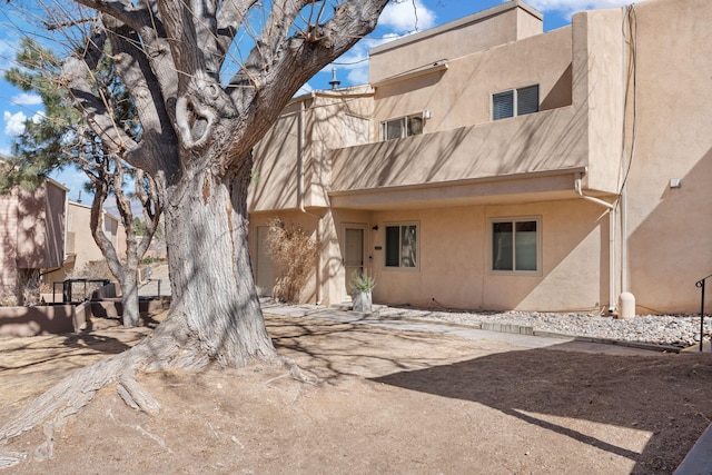 rear view of house featuring stucco siding