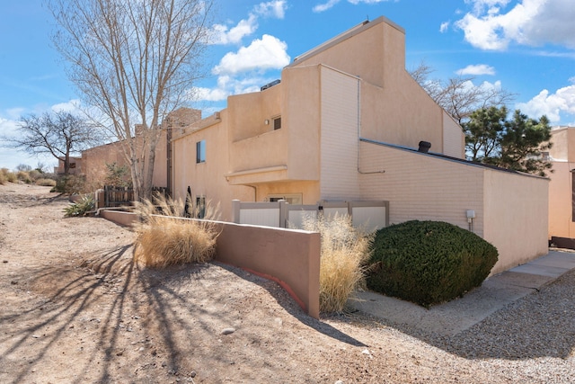 view of home's exterior with fence and stucco siding