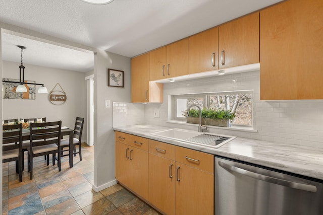 kitchen featuring pendant lighting, light countertops, decorative backsplash, stainless steel dishwasher, and a sink