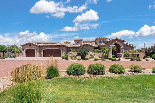 mediterranean / spanish-style home with stucco siding, driveway, a front yard, an attached garage, and a tiled roof