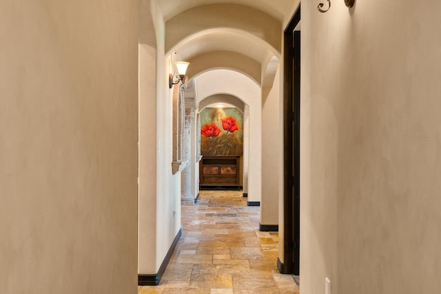 hallway with baseboards and stone tile floors