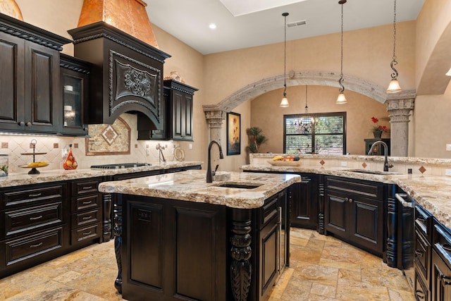 kitchen featuring stone tile flooring, decorative backsplash, pendant lighting, and a sink