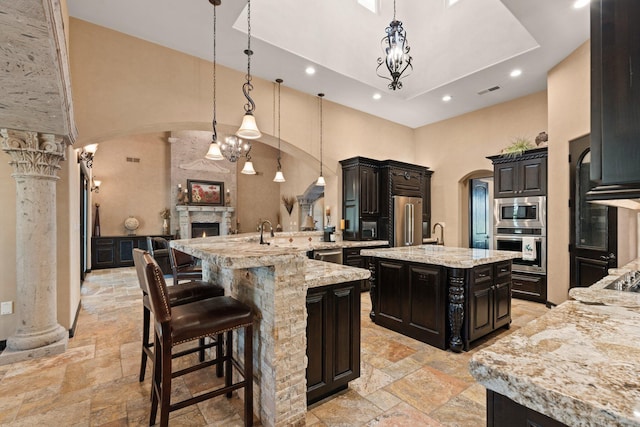 kitchen with ornate columns, stone tile floors, arched walkways, and appliances with stainless steel finishes