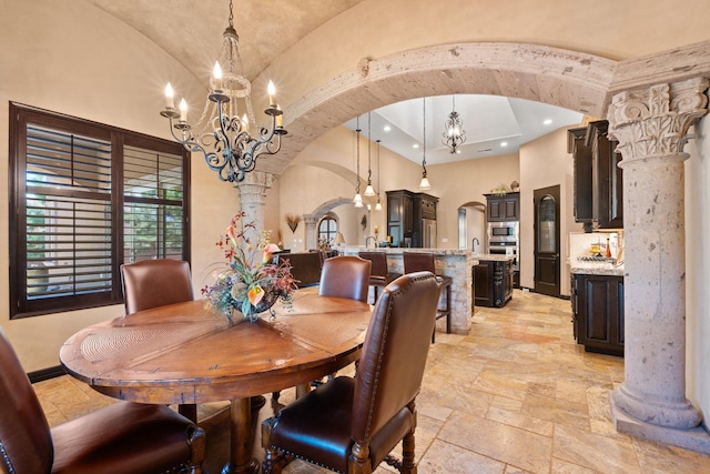 dining space with vaulted ceiling, stone tile floors, decorative columns, arched walkways, and a notable chandelier