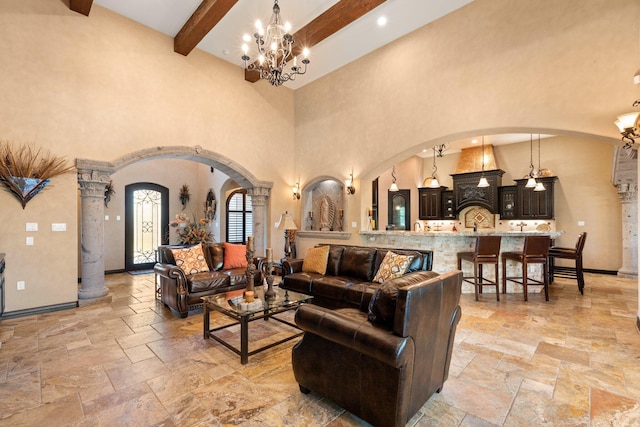 living room with arched walkways, a chandelier, beamed ceiling, and stone tile flooring