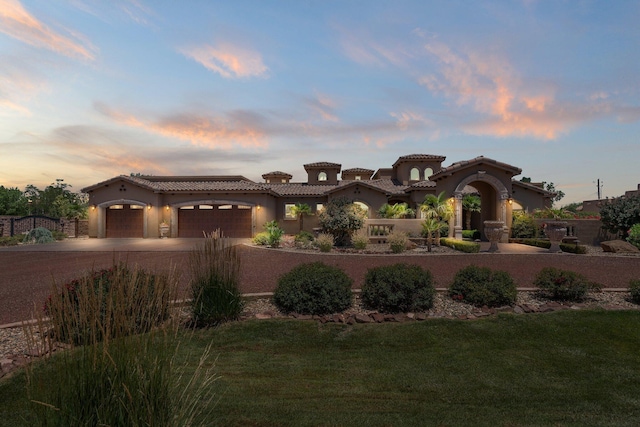 mediterranean / spanish-style home with a tiled roof, stucco siding, a yard, a garage, and driveway