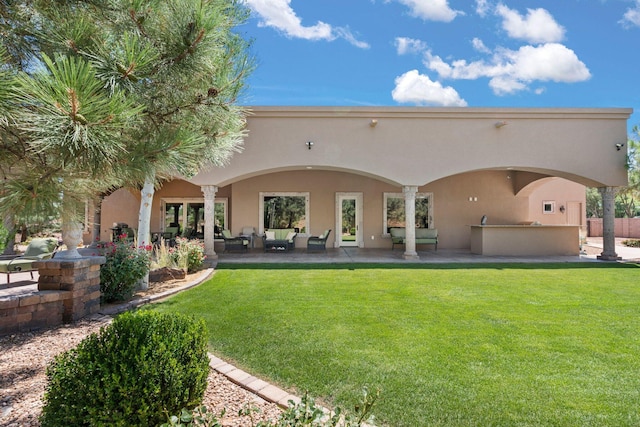 rear view of house featuring stucco siding, an outdoor hangout area, a lawn, and a patio area