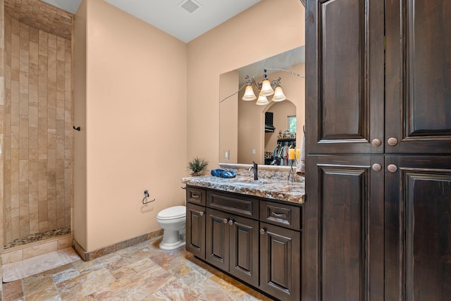 bathroom with visible vents, toilet, a tile shower, baseboards, and vanity