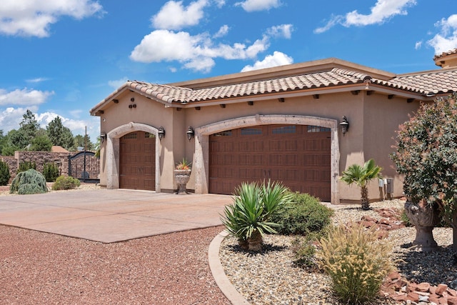 mediterranean / spanish house featuring a tiled roof, stucco siding, driveway, and a garage