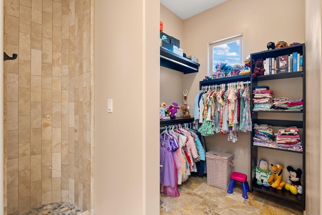 walk in closet featuring stone finish floor