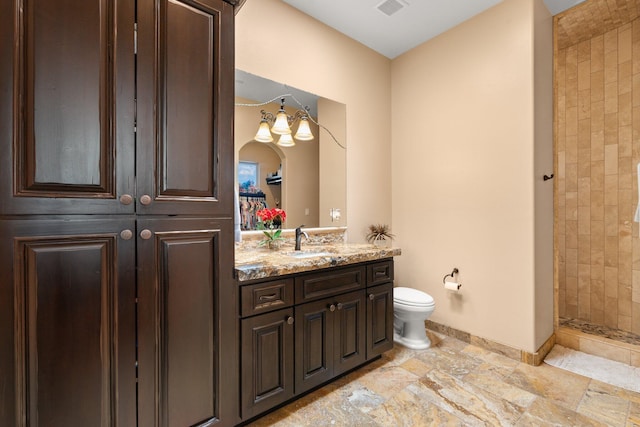 full bathroom with visible vents, toilet, stone tile floors, a tile shower, and vanity