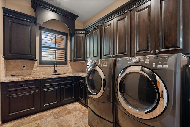 laundry area with separate washer and dryer, stone finish floor, cabinet space, and a sink