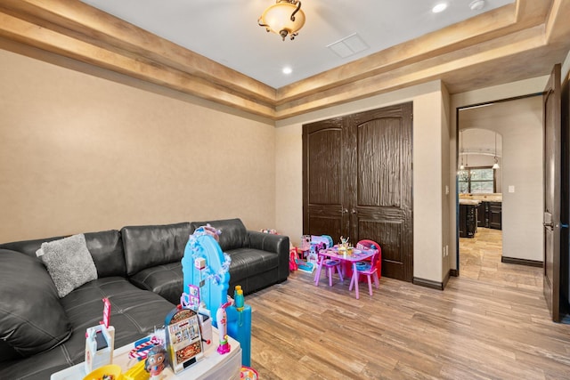 living room featuring visible vents, baseboards, recessed lighting, light wood-style floors, and a raised ceiling