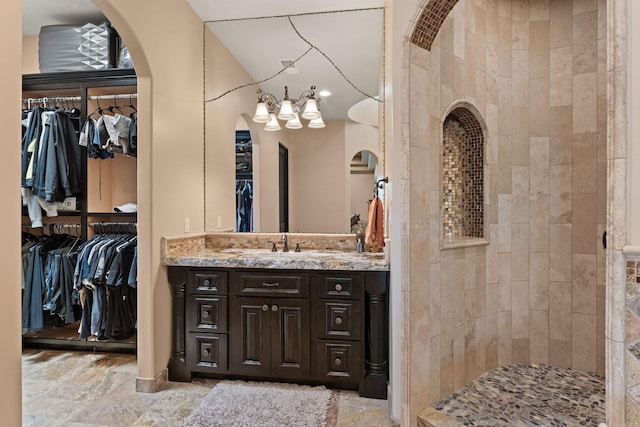 bathroom with a spacious closet, vanity, and a tile shower