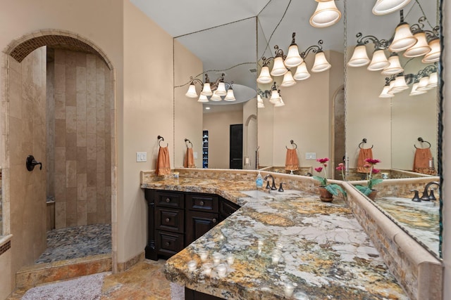 full bathroom featuring tiled shower and vanity