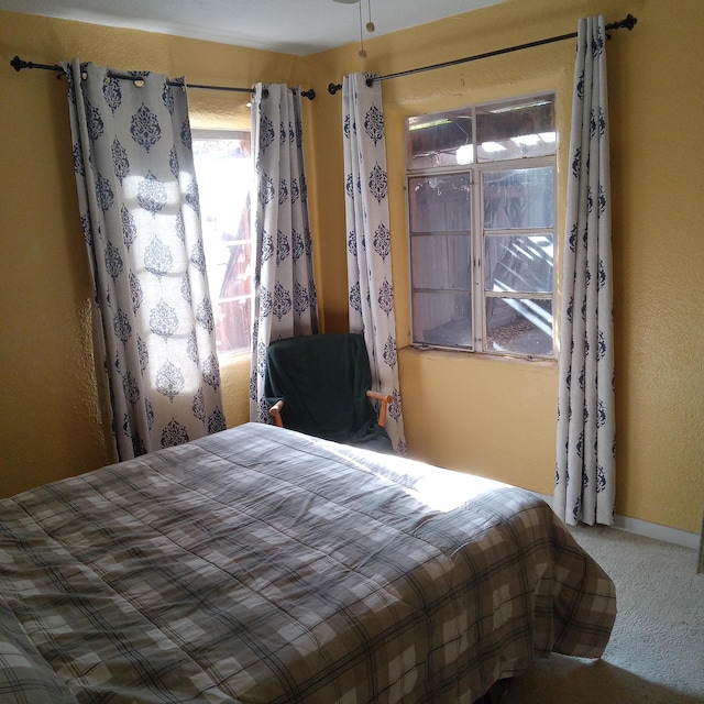 bedroom with carpet flooring, a textured wall, and baseboards