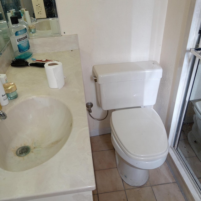 bathroom with tile patterned flooring, toilet, and a sink