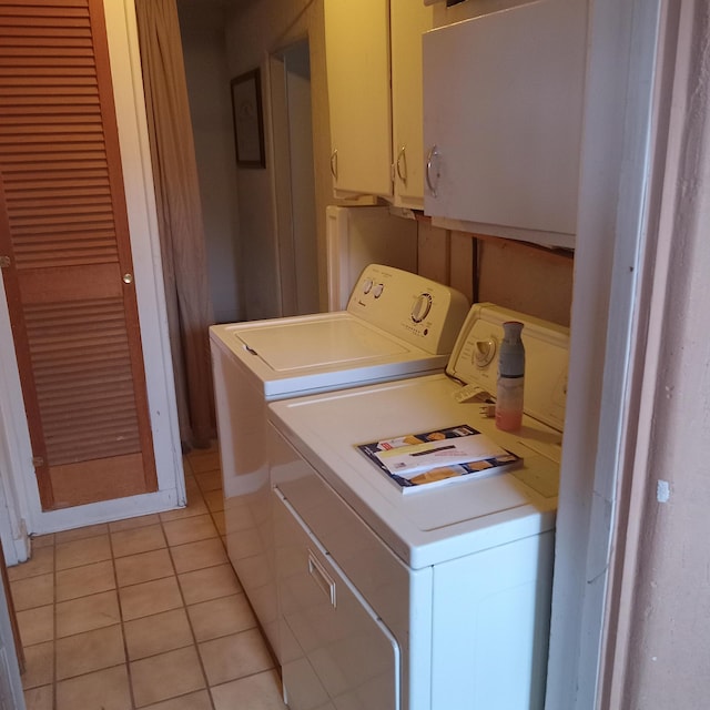 laundry area with light tile patterned floors, cabinet space, and washer and clothes dryer