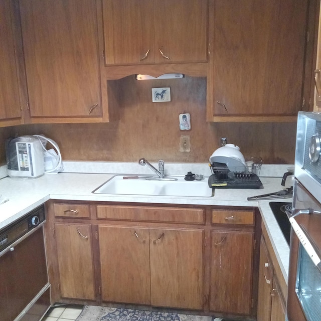 kitchen with a sink, dishwashing machine, brown cabinetry, and light countertops