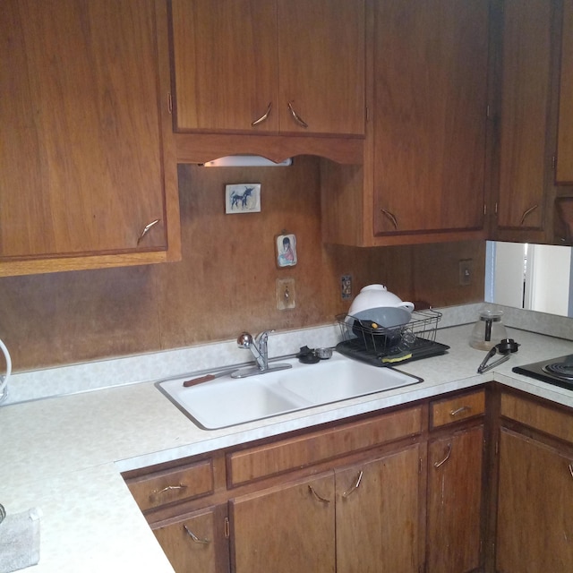 kitchen with brown cabinetry, light countertops, and a sink