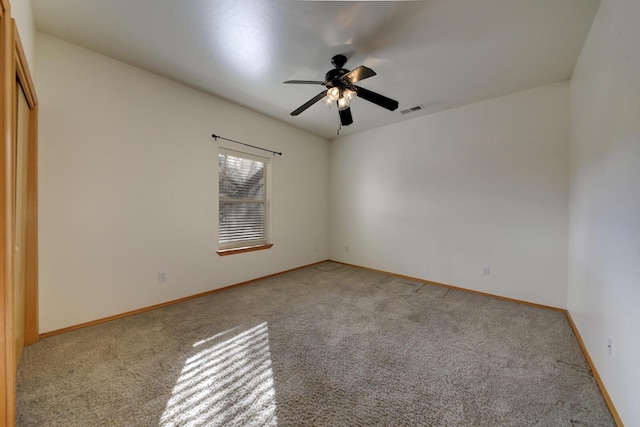 spare room with visible vents, light colored carpet, baseboards, and ceiling fan