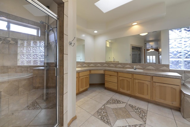 bathroom with vanity, a skylight, decorative backsplash, a shower stall, and tile patterned flooring