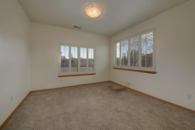 empty room with visible vents, carpet, and baseboards