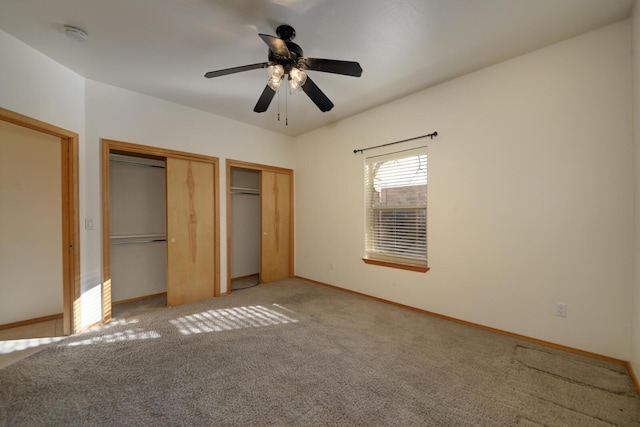 unfurnished bedroom featuring light colored carpet, two closets, baseboards, and a ceiling fan