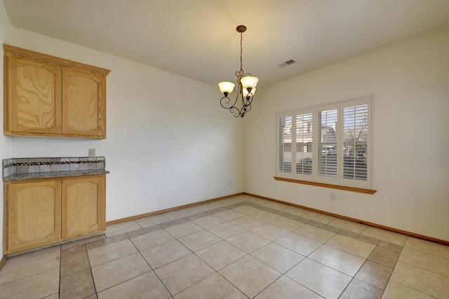 unfurnished dining area featuring visible vents, baseboards, a chandelier, and light tile patterned flooring