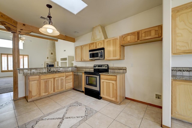 kitchen featuring a skylight, light tile patterned flooring, light brown cabinets, and appliances with stainless steel finishes