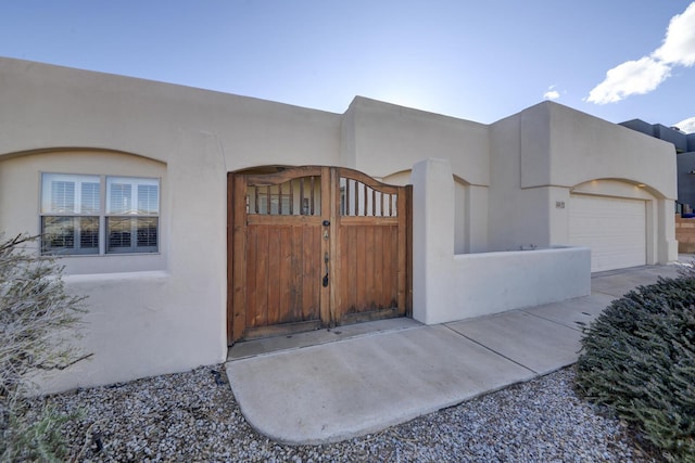 entrance to property with a gate and stucco siding